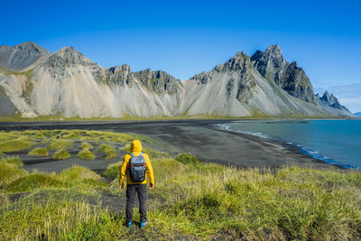 Man on lake by mountains against clear sky