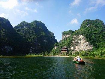 People on boat in lake against sky