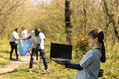 Side view of man using digital tablet while standing in park