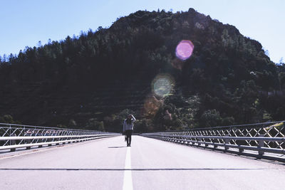 Full length of woman standing on bridge against mountain during sunny day