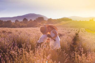 Kids kissing while standing on field against sky