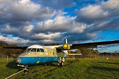 Broken airplane on field against sky