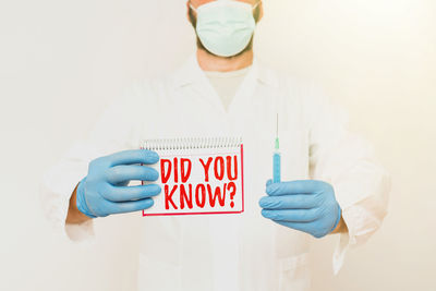 Midsection of man holding mobile over white background