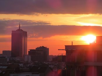 Buildings in city against romantic sky at sunset