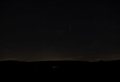 Silhouette landscape against sky at night