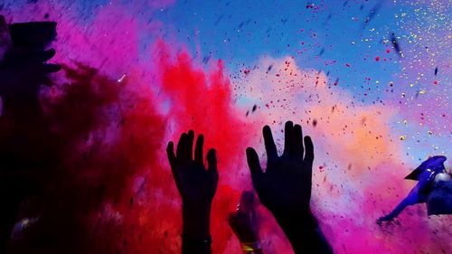 Close-up of hands against multi colored water