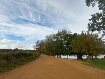 Scenic view of road amidst trees against sky