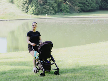 A young mother walks with her child in a park by the lake.