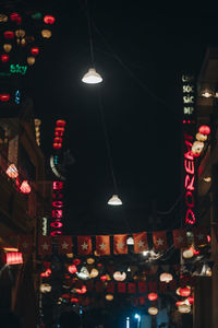 Low angle view of illuminated lanterns hanging in city at night