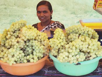 Portrait of smiling young woman with fruits in container