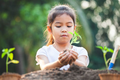 Close-up of girl holding plant in hand outdoors