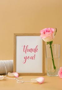 Wooden frame with greeting card text thank you delicate pink roses, spool of white cotton rope on