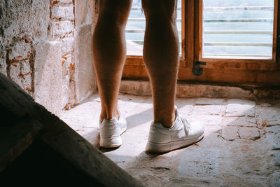 Low section of man standing by window