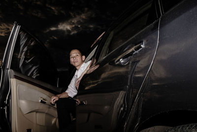 Low angle portrait of man sitting in car at night