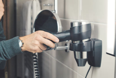 Midsection of woman holding hair dryer at home