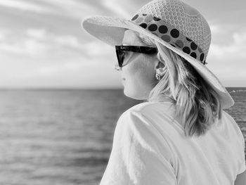 Portrait of woman wearing hat against sea