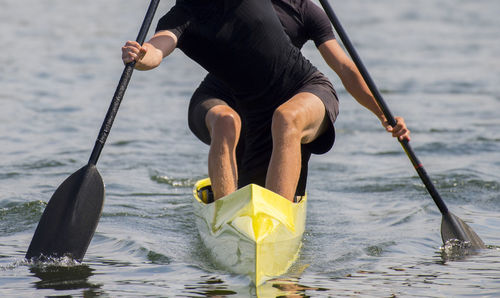 Midsection of men canoeing in lake