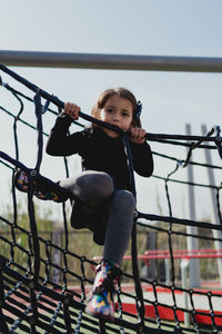 Four-year-old girl playing in the park, climbing in the daytime.