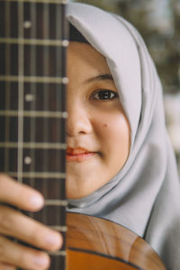 Portrait of girl wearing hijab holding guitar