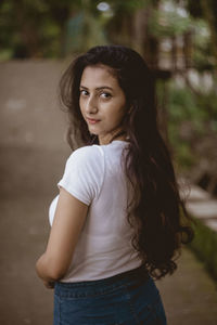 Portrait of beautiful woman standing against trees