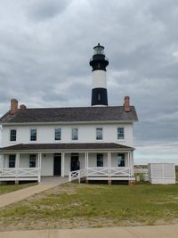 Lighthouse by building against sky