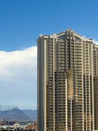 Low angle view of skyscraper against blue sky