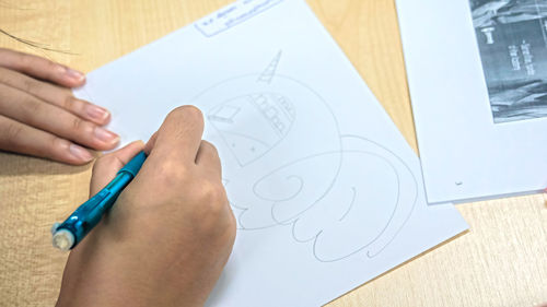 Cropped image of person making drawing on paper 