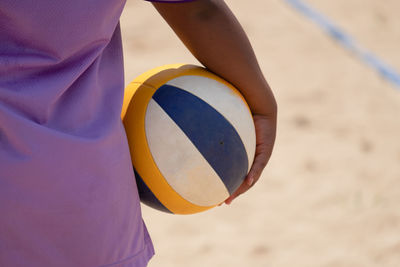 Close-up of person holding ball on sand