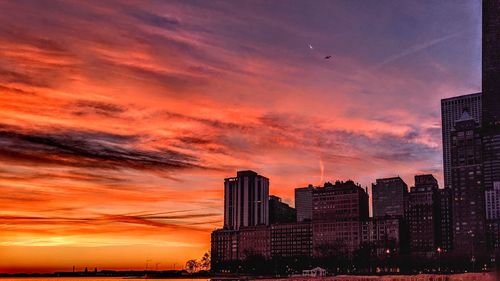 The sun rises painting the city sky amidst the moon