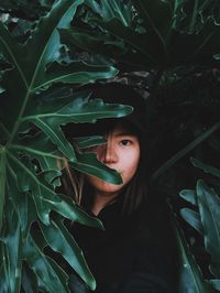 Portrait of young woman with green leaves