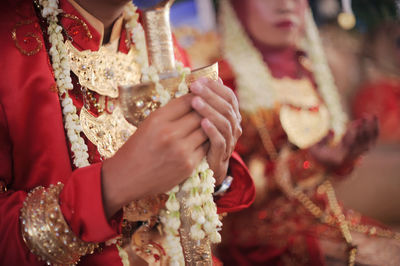 Midsection of bride holding bouquet