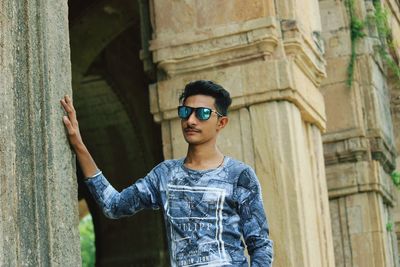 Portrait of young man standing against wall