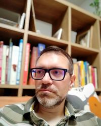 Man looking away against bookshelf at home