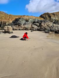 Man on rock formation on land against sky