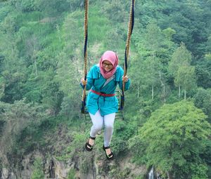 Full length of women climbing on rope in forest