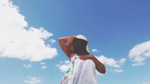 Low angle view of woman standing against blue sky