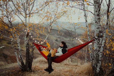 Couple relaxing on hammock near tree