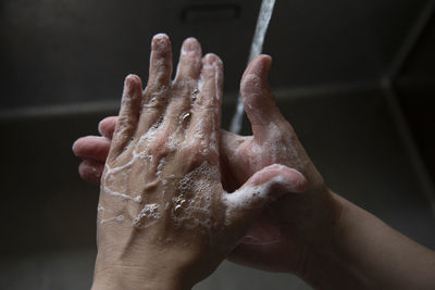 Close up of someone scrubbing their hands with soap in the sink