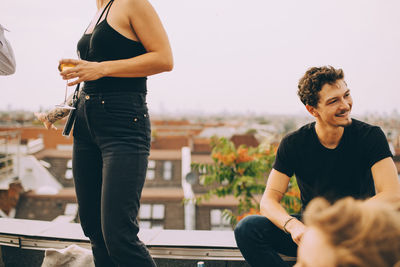 Woman with beer standing by friend looking away on terrace at party