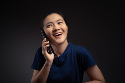 Portrait of smiling young woman against black background