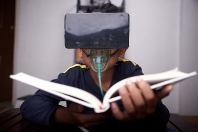 Close-up of boy wearing virtual reality simulator while reading book