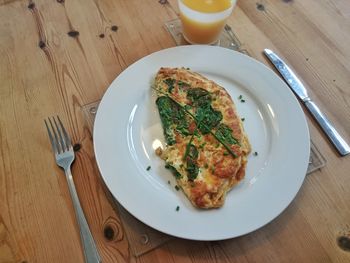 High angle view of omelet by drink on wooden table