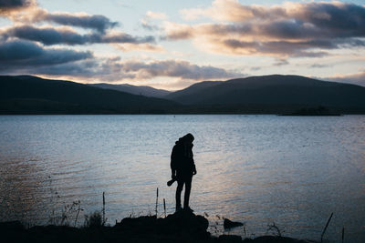 Silhouette of man standing in front of lake