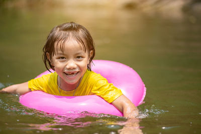 Portrait of smiling girl with inflatable ring swimming in lake