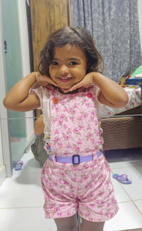 Portrait of a smiling girl standing against the wall