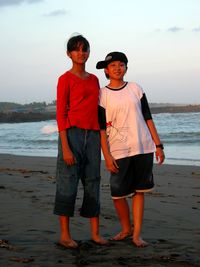 Full length of boys standing on beach against sea