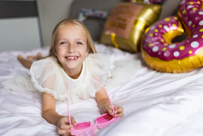 Portrait of smiling young woman sitting on bed at home