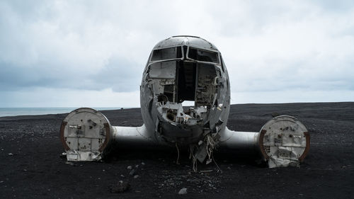 Abandoned airplane on beach against sky