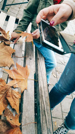 Close-up of woman using mobile phone on wood