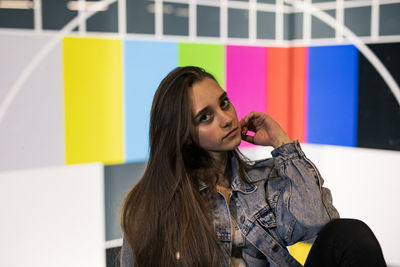 Portrait of young woman against multi colored wall